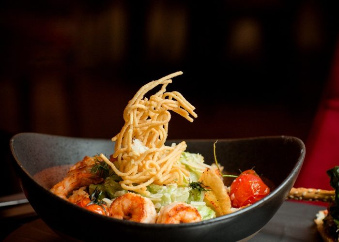 side view of shrimp caesar plate topped with potato shoestrings