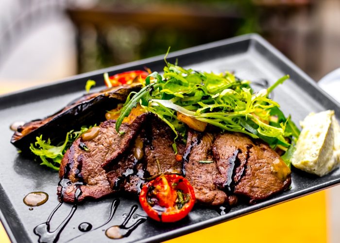 top view fried meat with eggplant tomato and arugula in a sauce on a tray